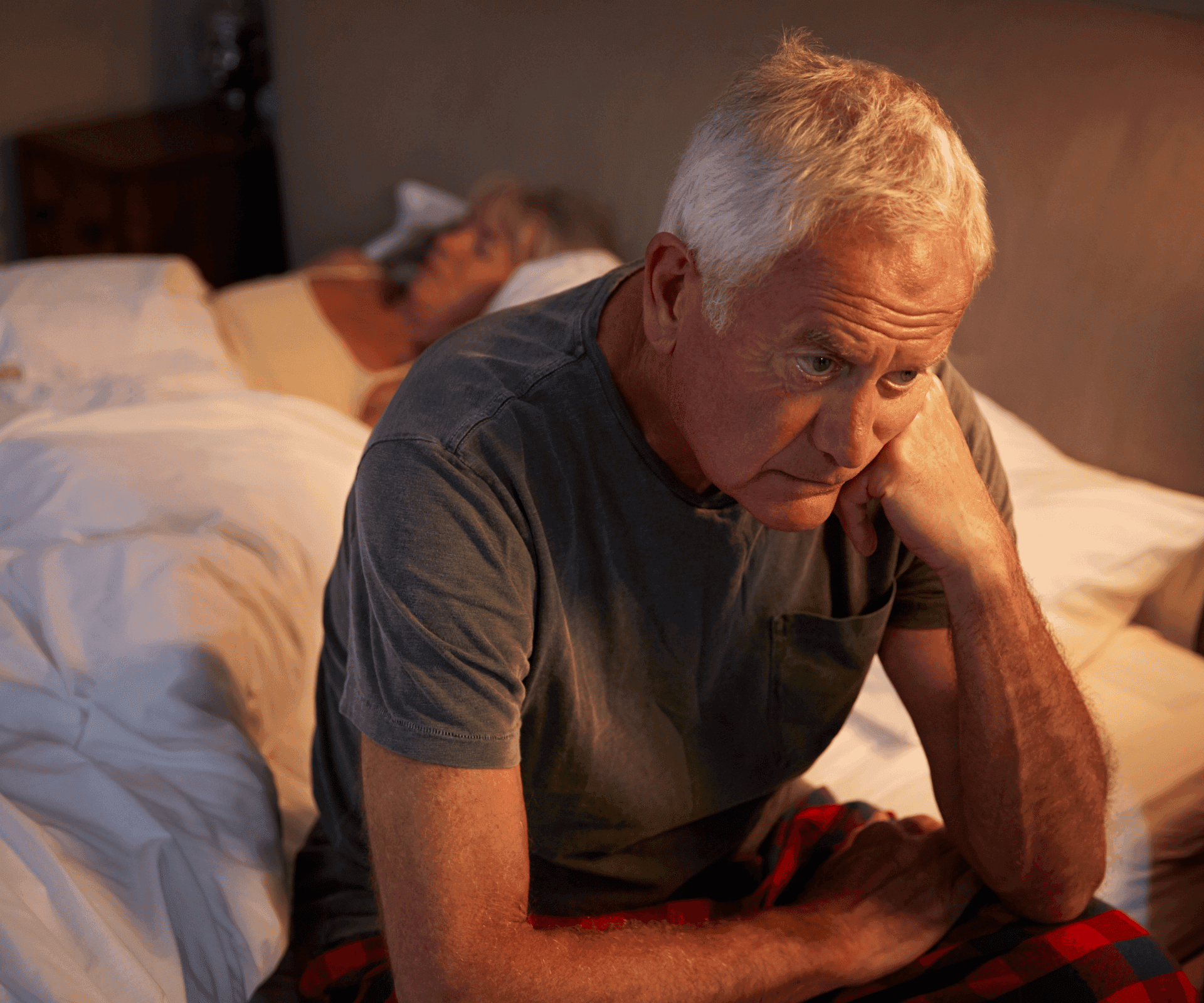 Man sitting on edge of bed at night due to urinary urgency