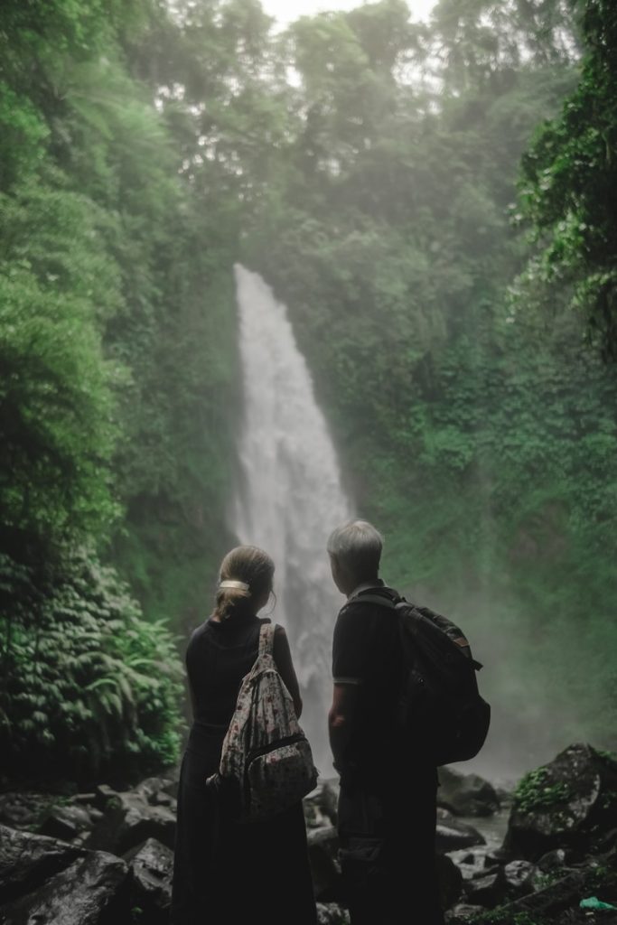 a couple of people standing in front of a waterfall